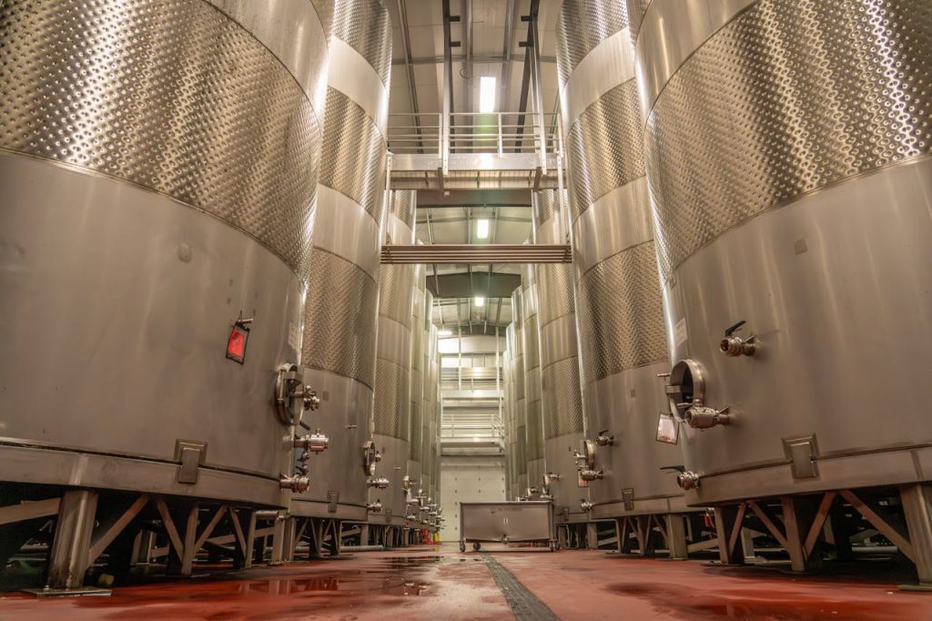 Interior of an industrial brewery with large, stainless steel fermentation tanks.